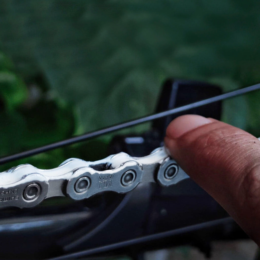 Finger touching Silca Super Secret chain lube on bicycle chain showing application