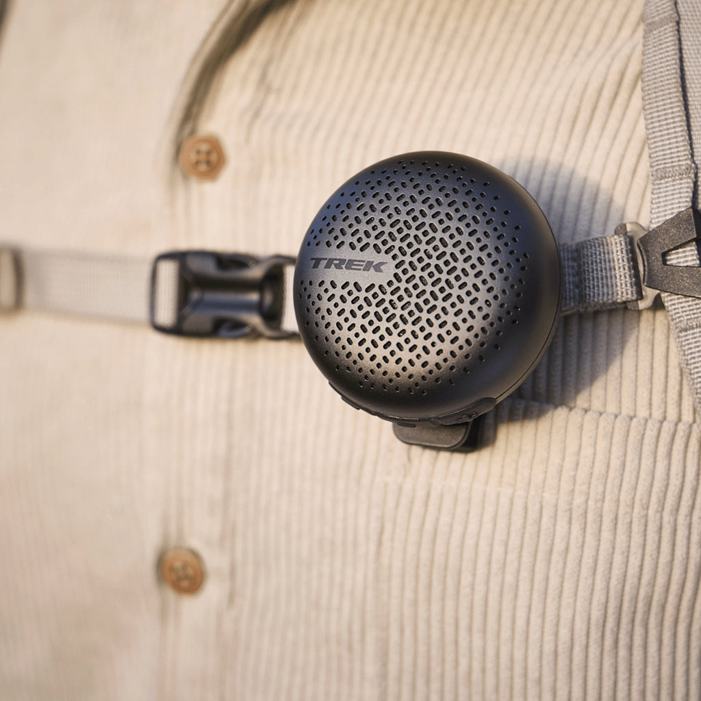 Trek BellBeats digital bike bell and speaker clipped to backpack strap using belt clip attachment